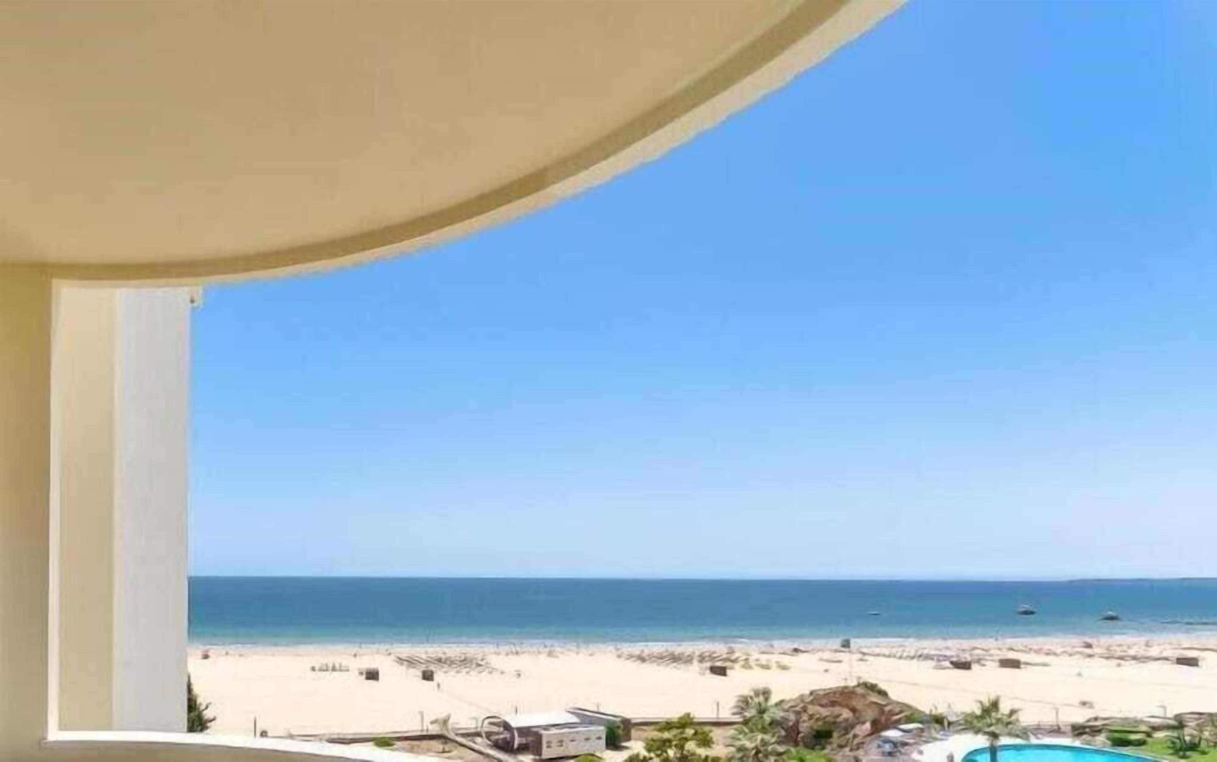 A beach view from a balcony with a clear sky.