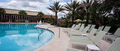 Una piscina con sillas de descanso y palmeras.