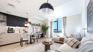 A modern living room with a sofa, coffee table, and dining area. - StayShort - Stunning Studio in Business Bay that Sleeps 2! (Business Bay)