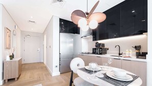 A modern kitchen with a dining area, featuring a central island, a refrigerator, and a coffee machine. - StayShort - Stunning Studio in Business Bay that Sleeps 2! (Business Bay)