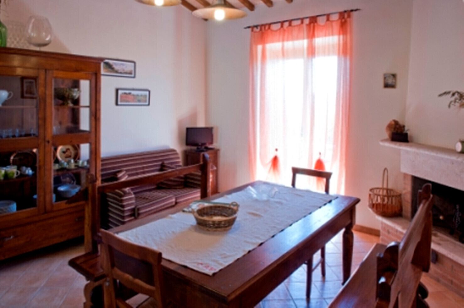 Un soggiorno tradizionale con un tavolo da pranzo in legno, sedie, un divano e un mobiletto con ante in vetro.