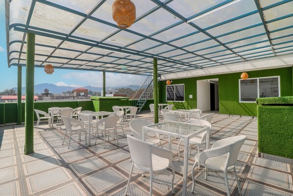 Eine Terrassenausstattung im Freien mit weißen Korbmöbeln und einer grünen Wand.