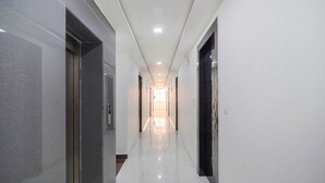 A hallway with marble flooring, doors on both sides, and recessed lighting. - HOTEL RIYA RAJ (Haridwar)