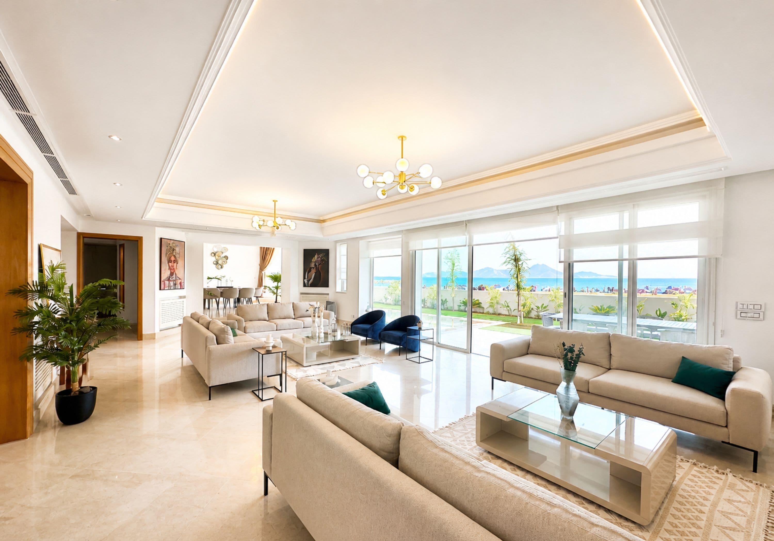 A spacious living room with a large window, a chandelier, and a view of the outdoors.