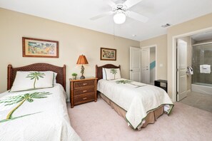 A bedroom with two beds, a ceiling fan, a nightstand with a lamp, and a door leading to a bathroom. - Na Hale O Keauhou C6 3 Bedroom Condo (Kailua-Kona)