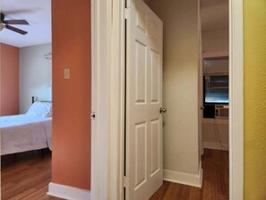 A bedroom with a bed, a ceiling fan, and a television in a hallway. - Cozy Church Street Apartment In Historic Galveston 2 Bedroom Apts (Galveston)