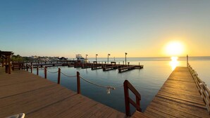 A wooden pier extending into calm waters with a sunset in the background. - Direct Bayfront Sunsets - Boat Docks - Pool - Fish 2 Bedroom Apts (South Padre Island)