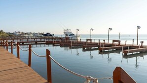 A wooden dock leading to a marina with boats and a clear view of the sea. - Direct Bayfront Sunsets - Boat Docks - Pool - Fish 2 Bedroom Apts (South Padre Island)