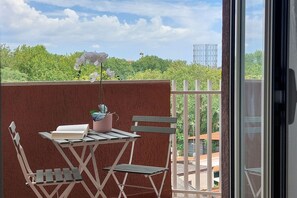 Ein Balkon mit Tisch, Stühlen und einer Topfpflanze.