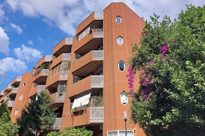 A multi-story residential building with balconies, a clear sky, and surrounding greenery. - Rifugio incantato sul Tevere (ROMA)