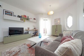 Ein modernes Wohnzimmer mit Flachbildfernseher, Couchtisch, Sofa und Bücherregal.
