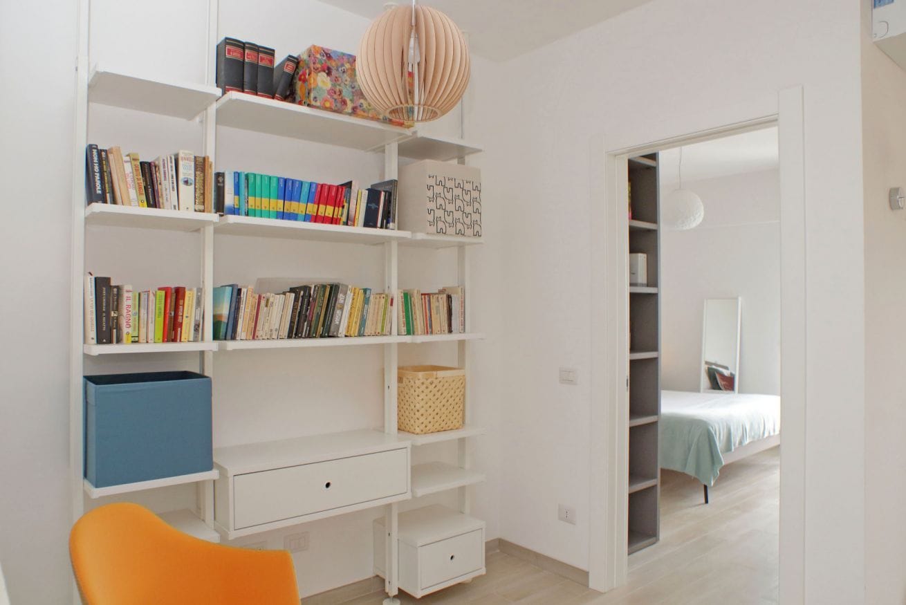Ein Zimmer mit Bücherregal, Schreibtisch und Bett.