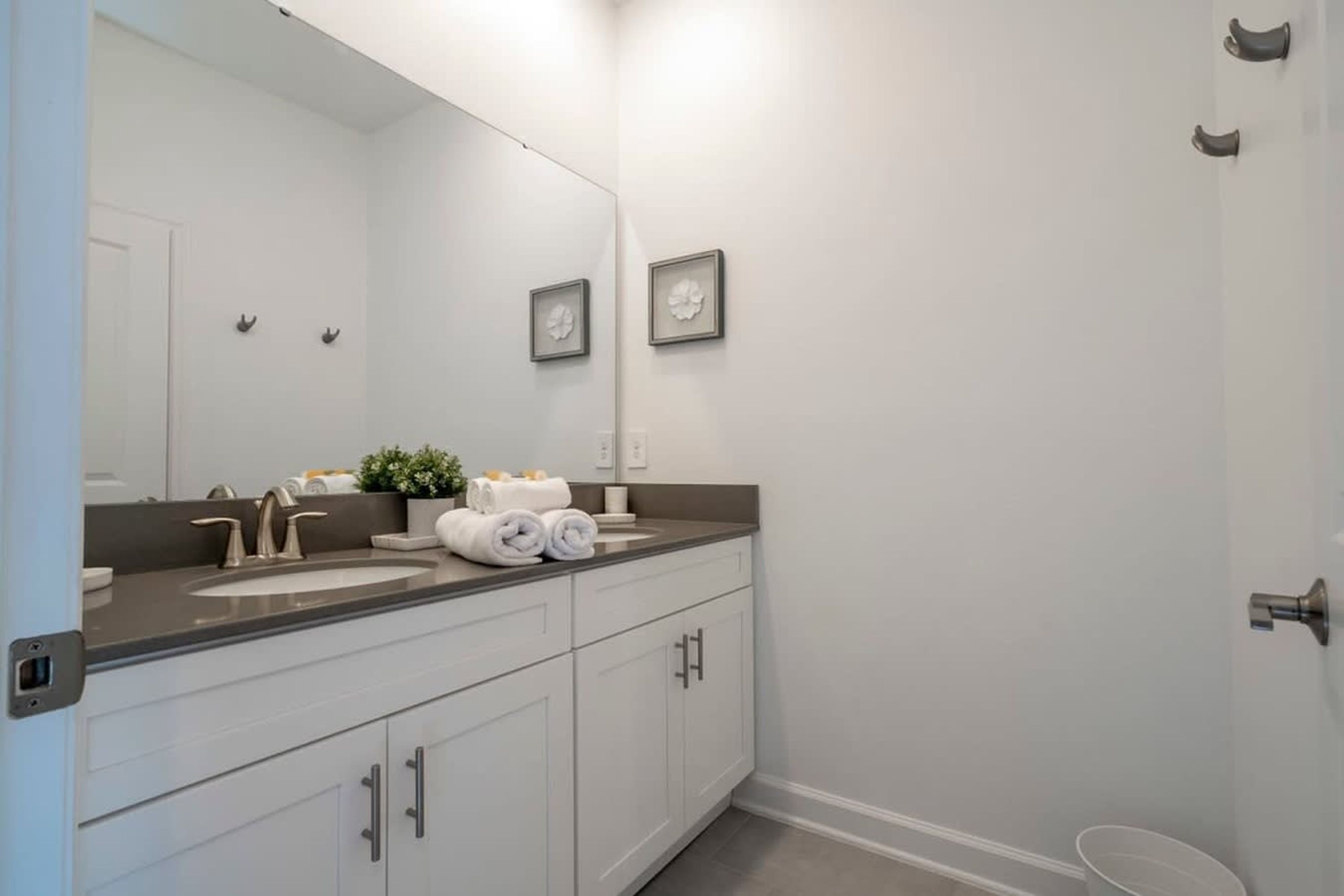 A bathroom with a double sink, a large mirror, and a towel rack.
