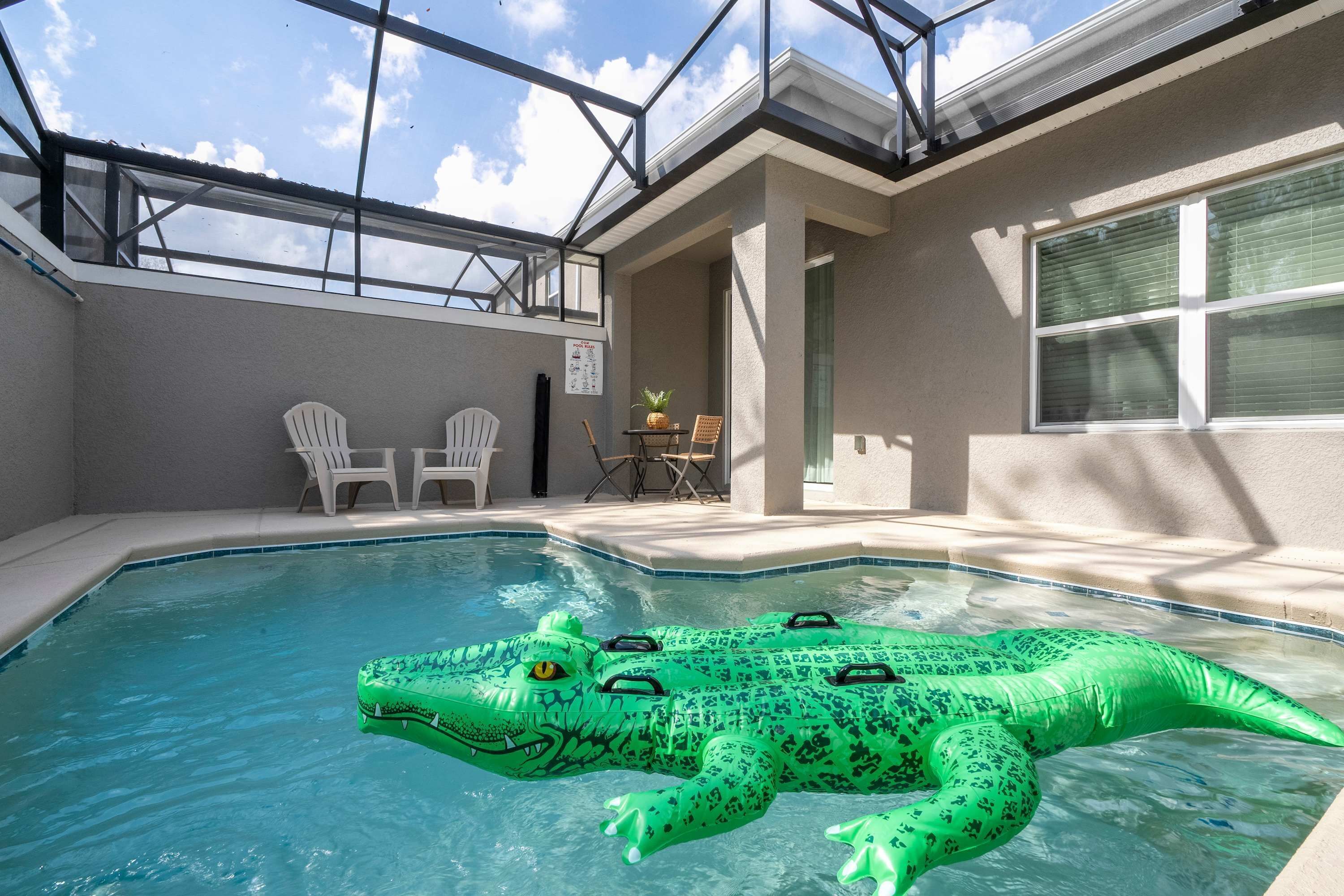 A swimming pool with a green inflatable alligator float.