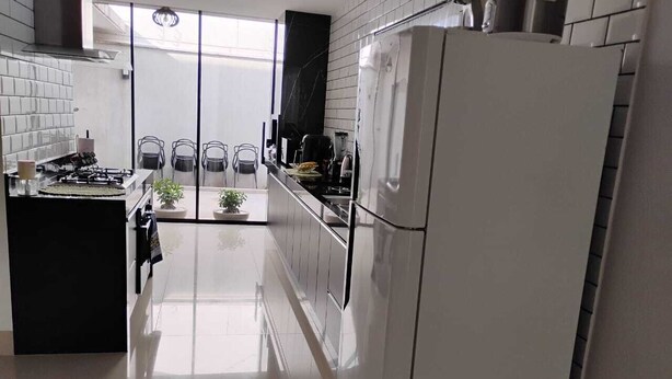 A modern kitchen with a central island, a refrigerator, and a dining area with chairs.