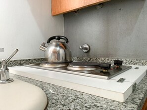 A kitchen with a stainless steel kettle on a portable gas stove, a white sink, and a granite countertop. - Gascon 13 in Buenos Aires (Buenos Aires)