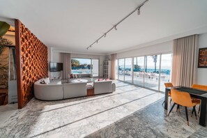 Ein modernes Wohnzimmer mit einer großen Eckcouch, einem Esstisch mit Stühlen und Blick ins Freie.