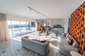 Ein modernes Wohnzimmer mit einer großen Couch, einem Couchtisch und Blick auf die Stadt.