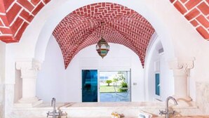 Un baño con dos lavamanos, un amplio arco de ladrillo y vistas al exterior.