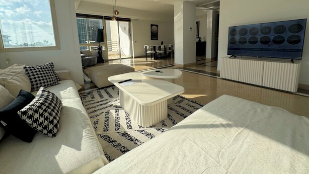 A modern living room with a sofa, coffee table, and a TV mounted on the wall. - Black & White: Modern & Spacious (Tunis)