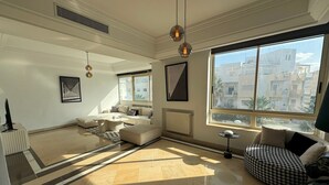 A spacious living room with a large window, a sofa set, a coffee table, and a television. - Black & White: Modern & Spacious (Tunis)