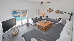 Uma sala de estar moderna com uma televisão grande, uma mesa de centro de madeira e um conjunto de sofá.