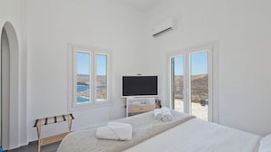 Um quarto com uma cama, televisão e vista para o mar.