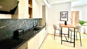 Una cucina moderna con un piano di lavoro in marmo nero, forno integrato e zona pranzo con due sedie e un tavolo.