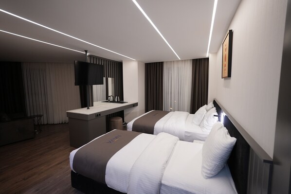 Una habitación de hotel moderna con dos camas, un escritorio, un televisor de pantalla plana y un espejo grande.