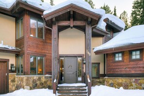 A wooden lodge with a stone foundation, a wooden porch, and a snow-covered entrance. - Belemere Lodge in Blue River (Blue River)