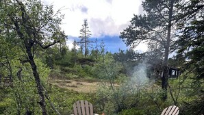Una terraza de madera con sillas Adirondack y un hogar para fuego.