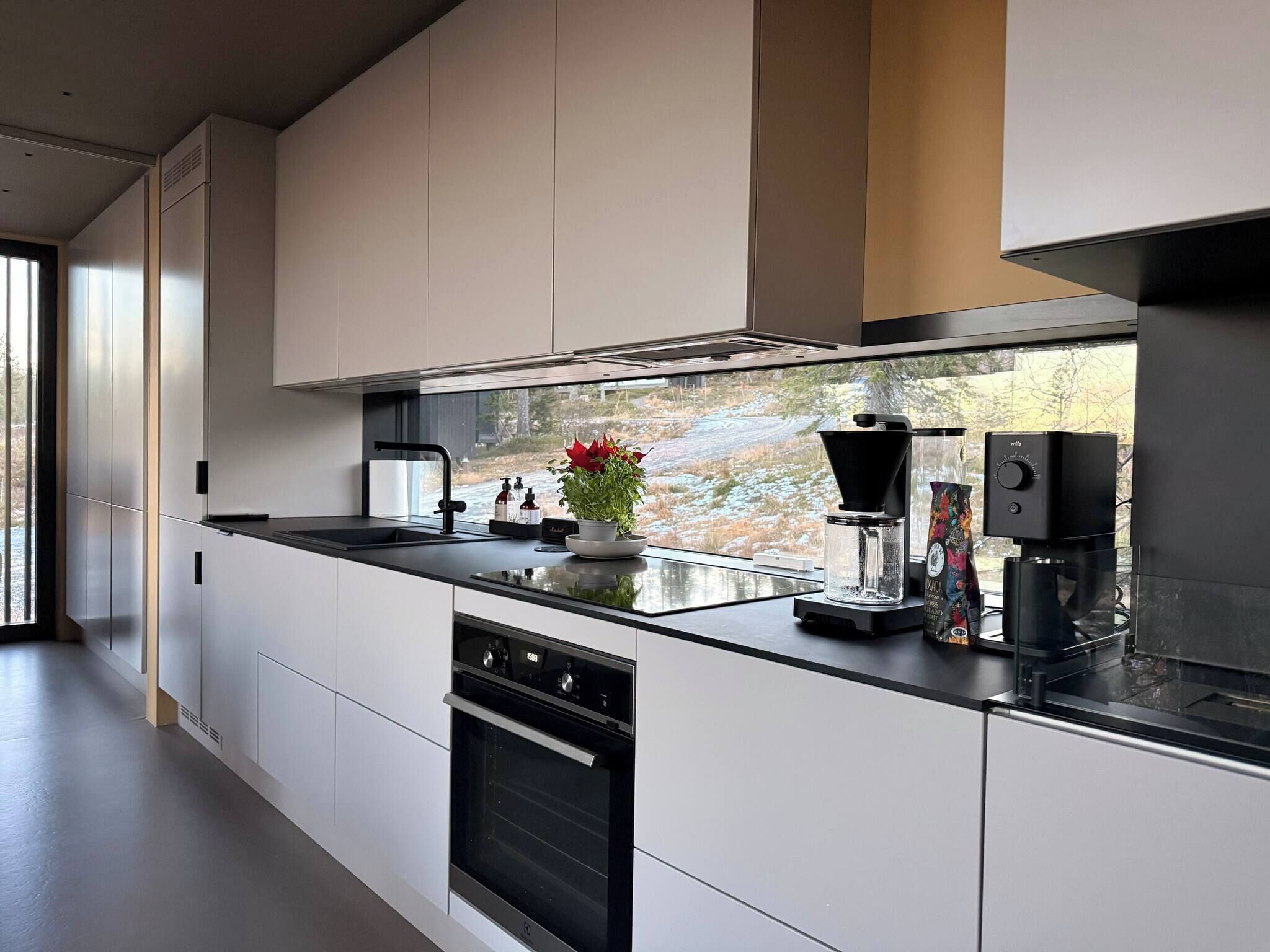 Una cocina moderna con una isla grande, horno empotrado y cafetera.