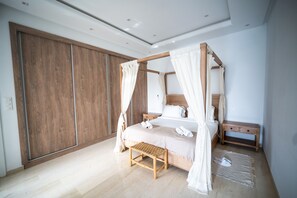 A modern bedroom with a four-poster bed, wooden wardrobe, bedside table, and a bench. - Modernity Villa exceptionnelle à Hammamet Centre (Hammamet Sud)