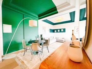 A modern living room with a green accent wall, a round dining table with chairs, a sofa, and a floor lamp. - The Perfect View in Site archéologique de Carthage (Site archéologique de Carthage)