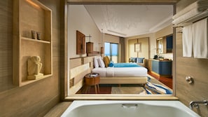 Ein modernes Hotelzimmer mit einem großen Bett, einem Schreibtisch und einem Badezimmer mit einer Badewanne.