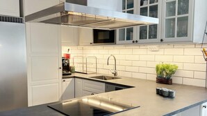 A modern kitchen with white cabinetry, a stainless steel sink, and a black countertop. - 4 Star Holiday Home in Ingaro (Värmdö)