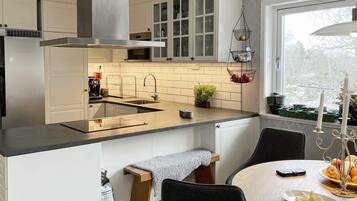 Cozinha moderna com ilha central, eletrodomésticos de aço inoxidável e janela com vista.