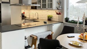 A modern kitchen with a central island, white cabinetry, and a window with a view of trees. - 4 Star Holiday Home in Ingaro (Värmdö)