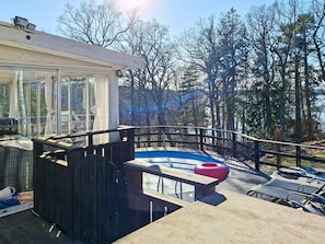Um deck moderno ao ar livre com estrutura de vidro, piscina e vista para uma área arborizada.