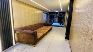 Un interior moderno con un sofá en un pasillo, una pared con estampado y una puerta que da al exterior.