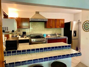 A kitchen with a stove, oven, refrigerator, and wooden cabinets. - Casa Jazmín by Comalli • Comala Magical Town, Mexico (Comala)