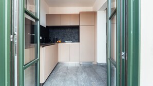 Een smalle keuken met beige kastjes, een zwart aanrecht en een betegelde vloer.