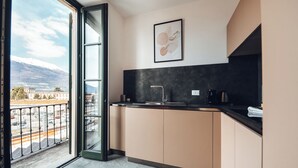 Een moderne keuken met een groot raam, een zwart aanrecht en uitzicht op een besneeuwde berg.