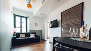 Een moderne woonkamer met een bank, een eettafel en een aan de muur bevestigde televisie.