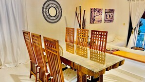 Un coin repas avec une table et des chaises en bois, un élément décoratif mural et une vue sur l’extérieur.