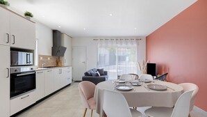 Eine moderne Küche mit weißen Schränken, einem eingebauten Backofen und einem Essbereich mit rundem Tisch und Stühlen.
