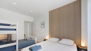 Ein Hotelzimmer mit Stockbetten, einem großen Bett mit zusammengerollten Handtüchern, einer Wand aus Holzslattern und einem gerahmten Schild.
