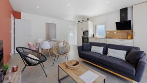Ein modernes Wohnzimmer mit einer Couch, einem Couchtisch und einem Essbereich mit Stühlen und einem Tisch.