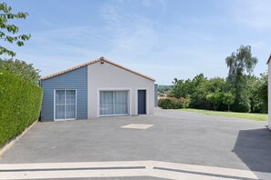 Een gebouw met twee verdiepingen, een blauwe gevel, grote schuifdeuren en een plat dak.
