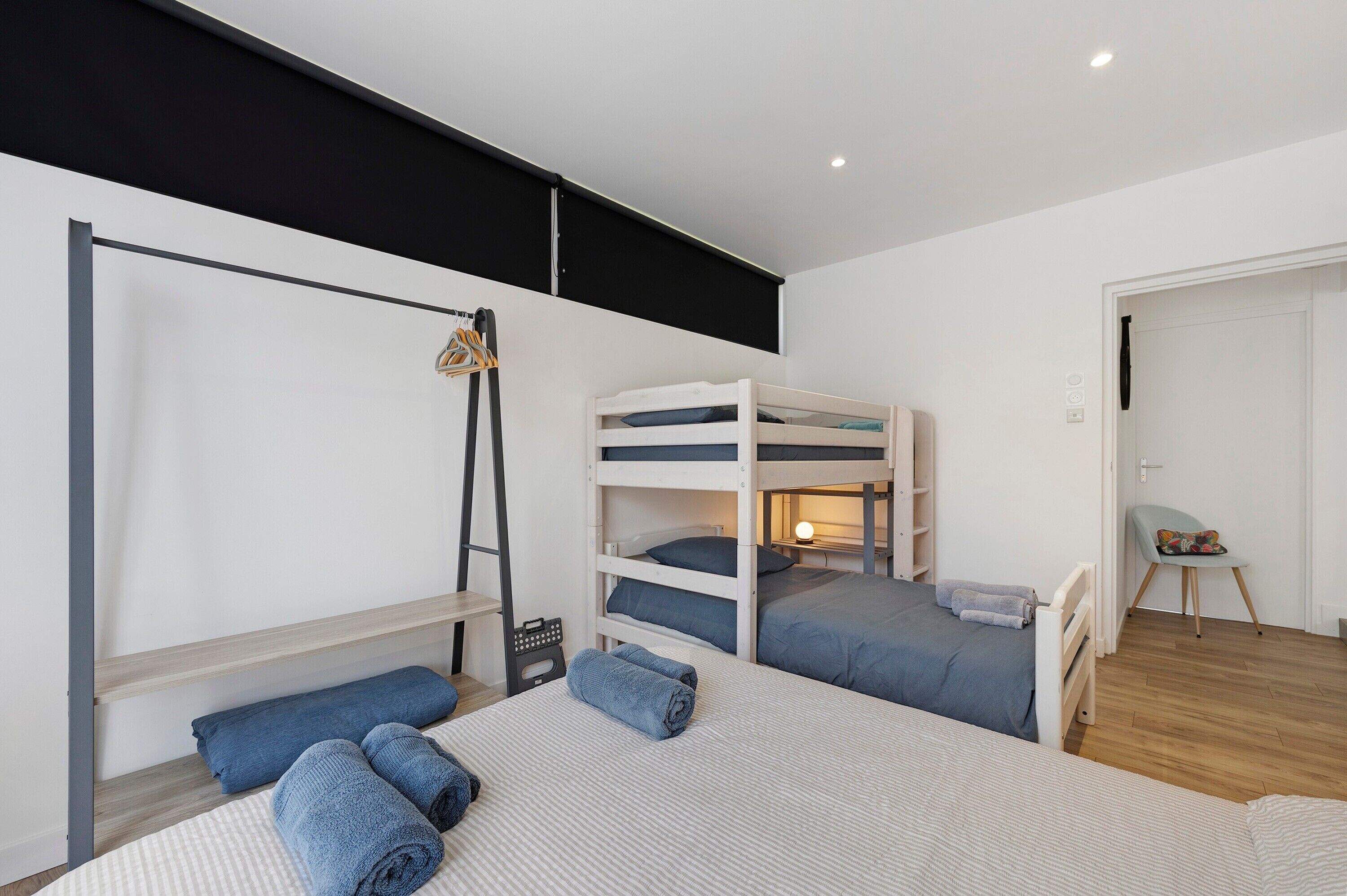 Une chambre avec des lits superposés, un bureau et une chaise.